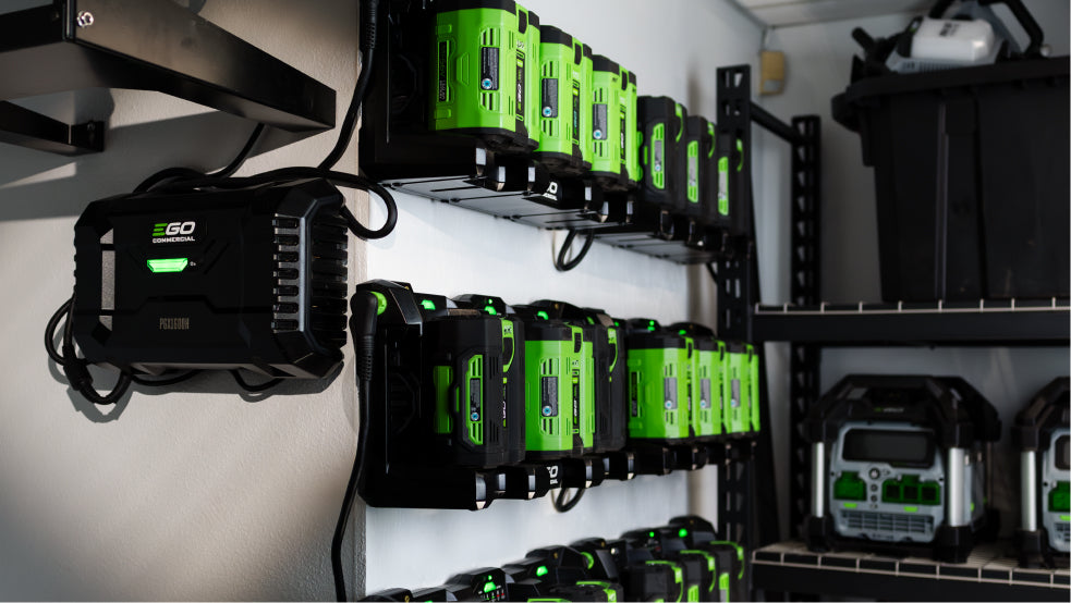 Row of green and black batteries and chargers on shelves in a storage area